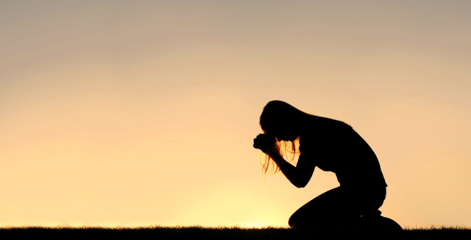 Woman kneeling and praying intently